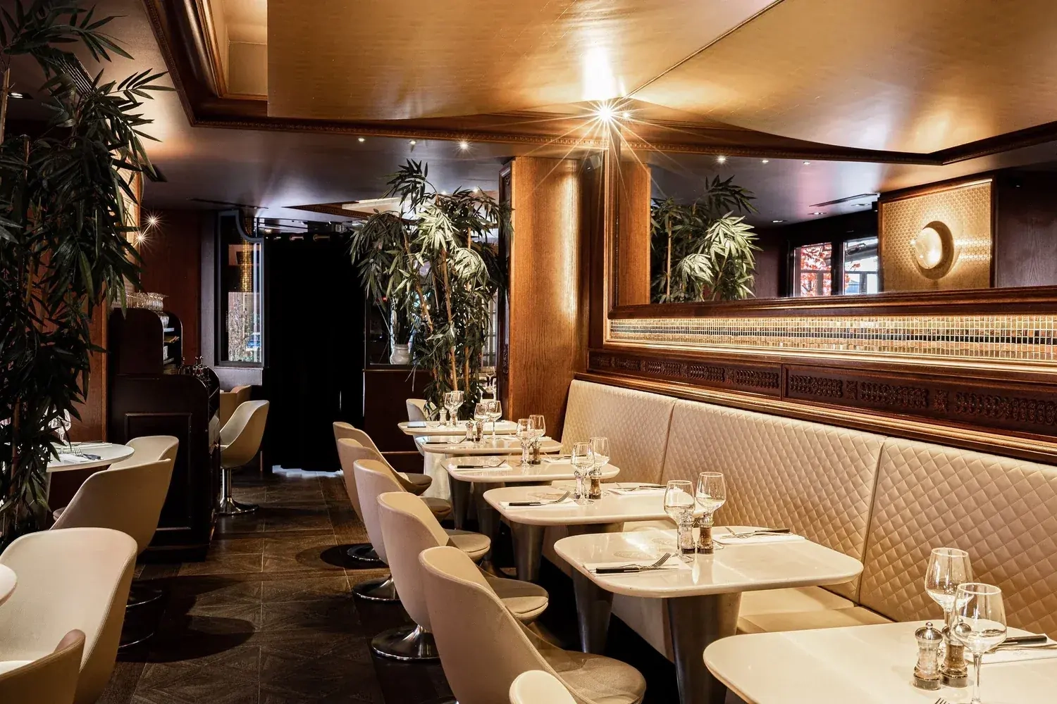 The main dining room with quilted banquettes, set tables and bamboo