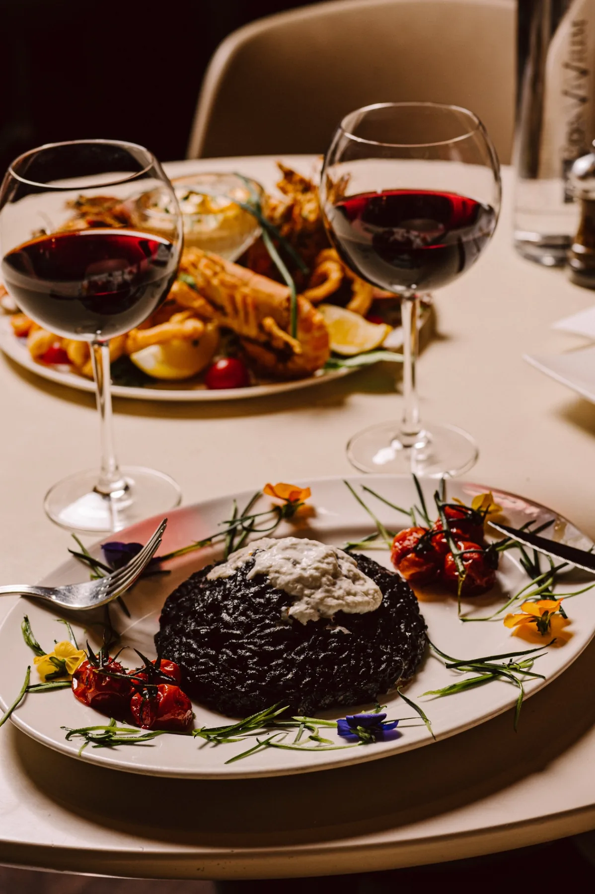 Risotto à l'encre de seiche et burrata, verres de vin rouge